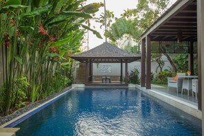 A swimming pool with a covered seating area, surrounded by lush tropical plants. - Alaya Dedaun Kuta (Legian)
