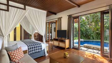 A bedroom with a bed, a TV, a coffee table, and a view of a swimming pool.