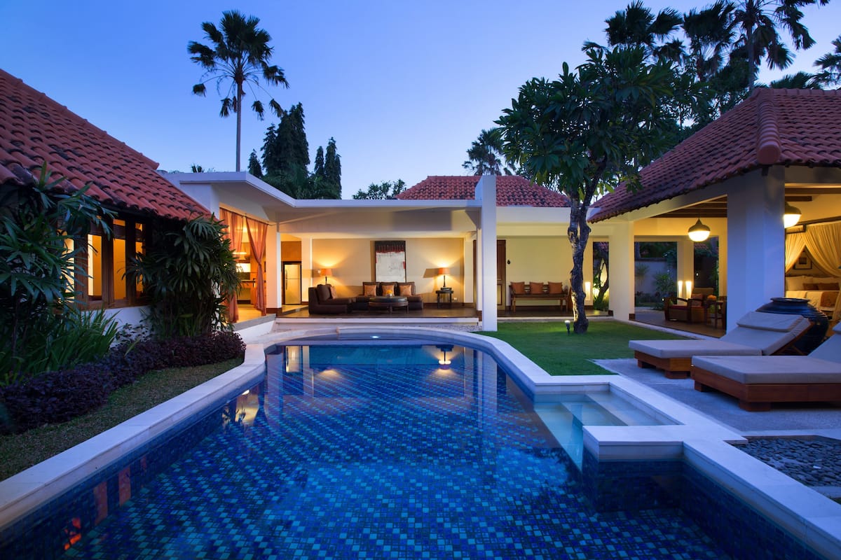 A modern house with a swimming pool, outdoor seating, and a well-lit patio area.