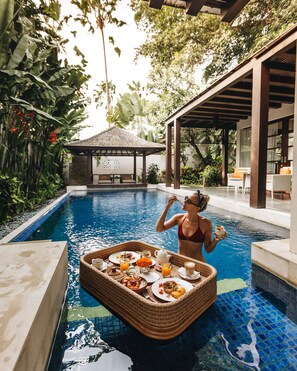 A woman in a red bikini by a pool with a wicker tray of food and drinks. - Alaya Dedaun Kuta (Legian)