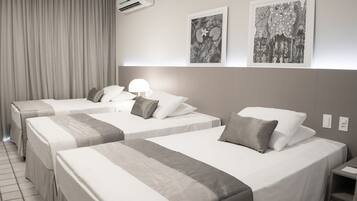 A hotel room with two beds, a nightstand, a lamp, and two framed artworks on the wall.