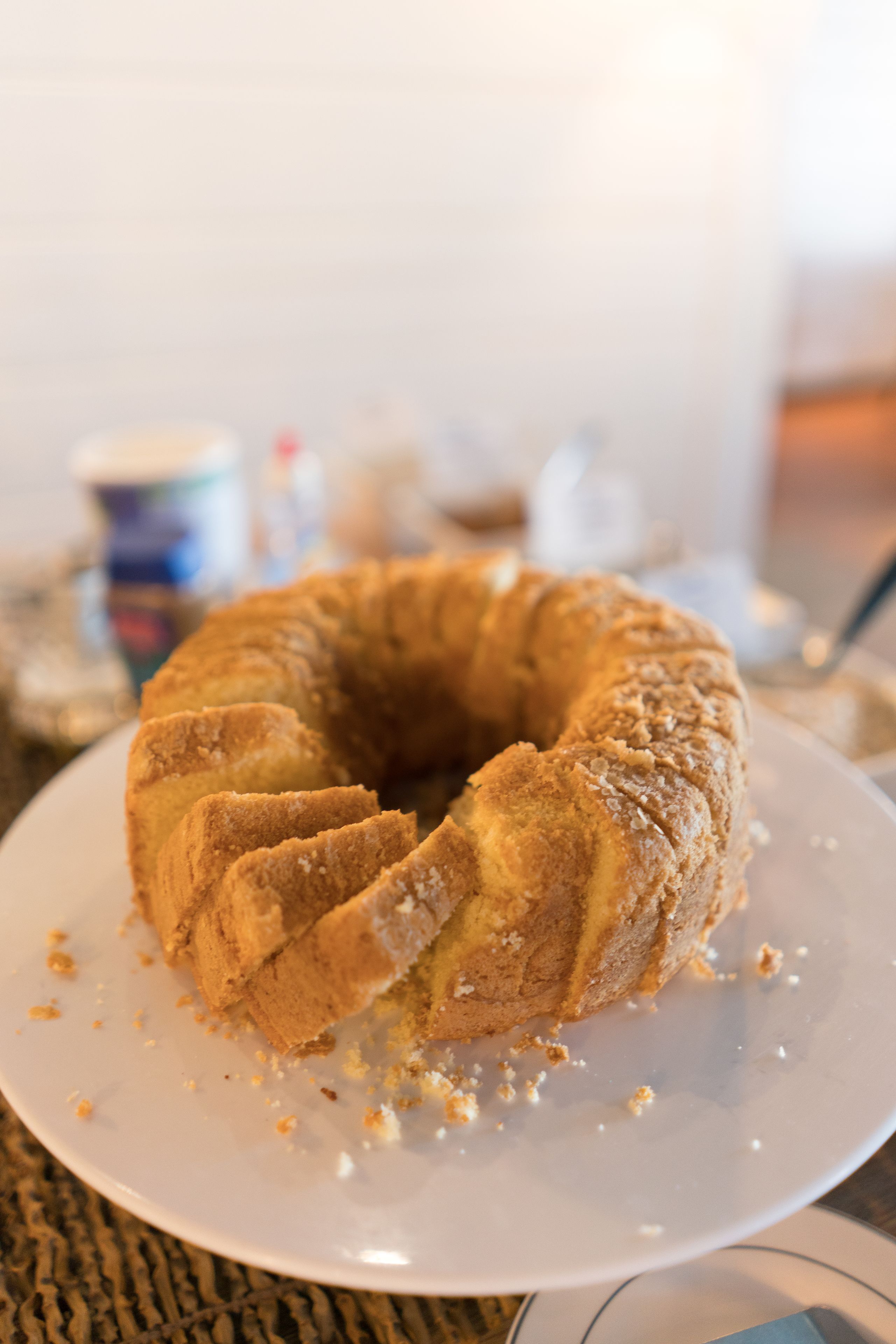 Um bolo bundt em um prato branco, com migalhas ao redor.