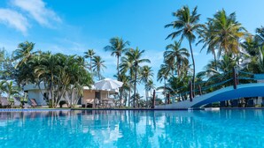 Une piscine à l’eau d’un bleu cristallin, entourée de palmiers et de chaises longues.