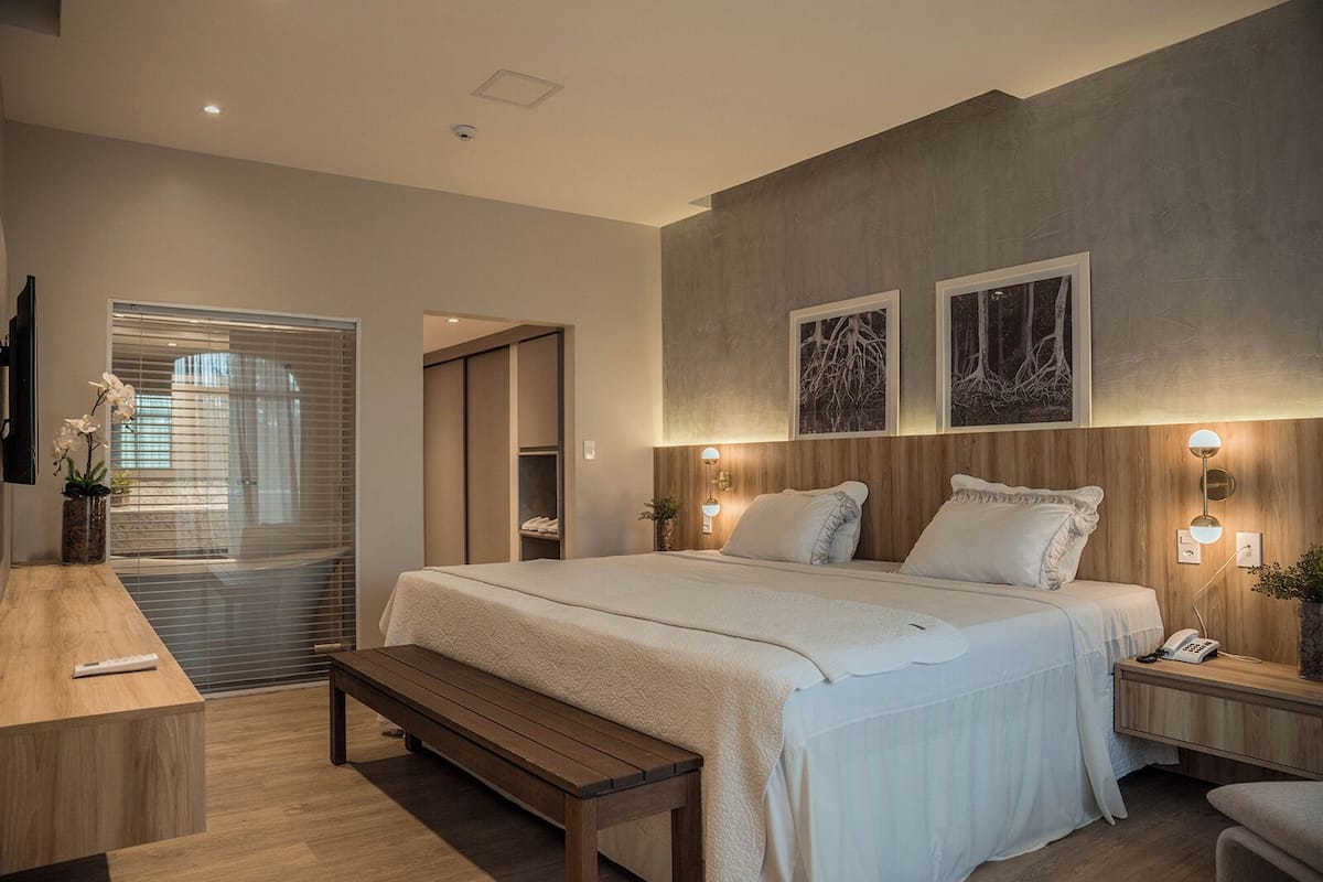 A modern bedroom with a large bed, bedside tables, a desk, and a bench.