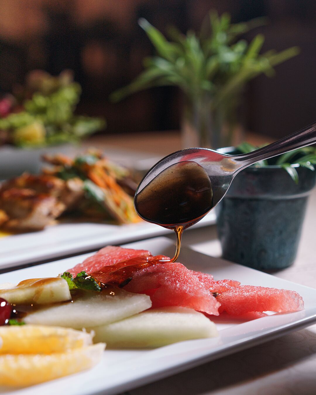 Une assiette contenant divers aliments et une cuillère versant de la sauce.