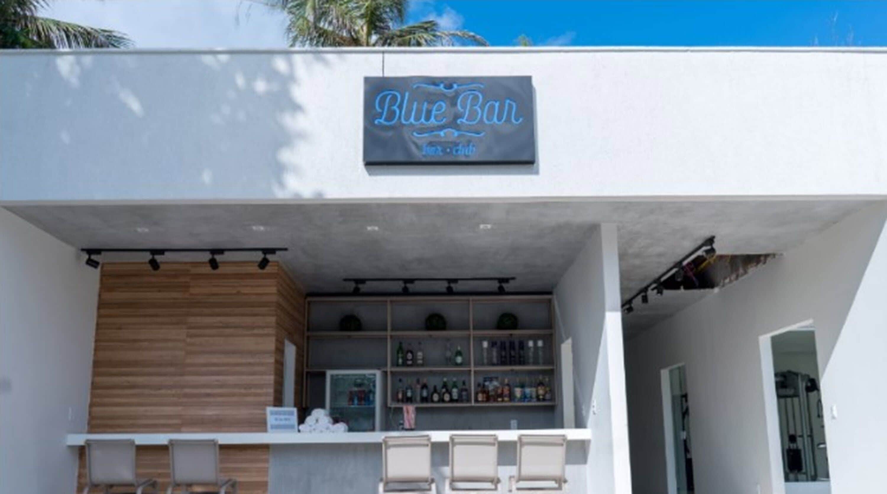 A bar named "Blue Bar" with a wooden counter and shelves of bottles.