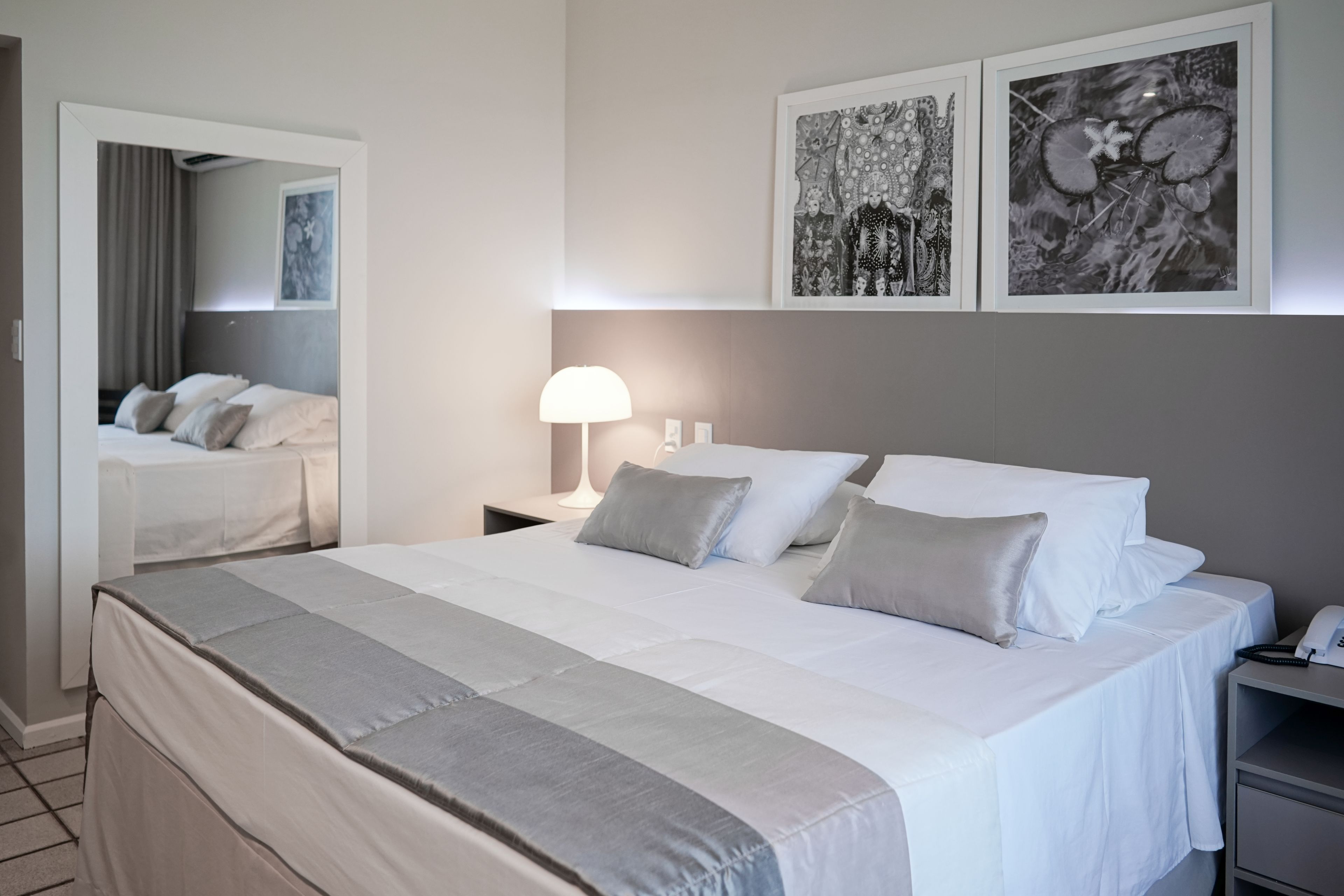A hotel room with a large bed, a bedside table with a lamp, and artwork on the wall.