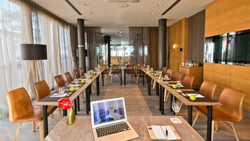 A conference room with long tables, chairs, a laptop, and a vase.