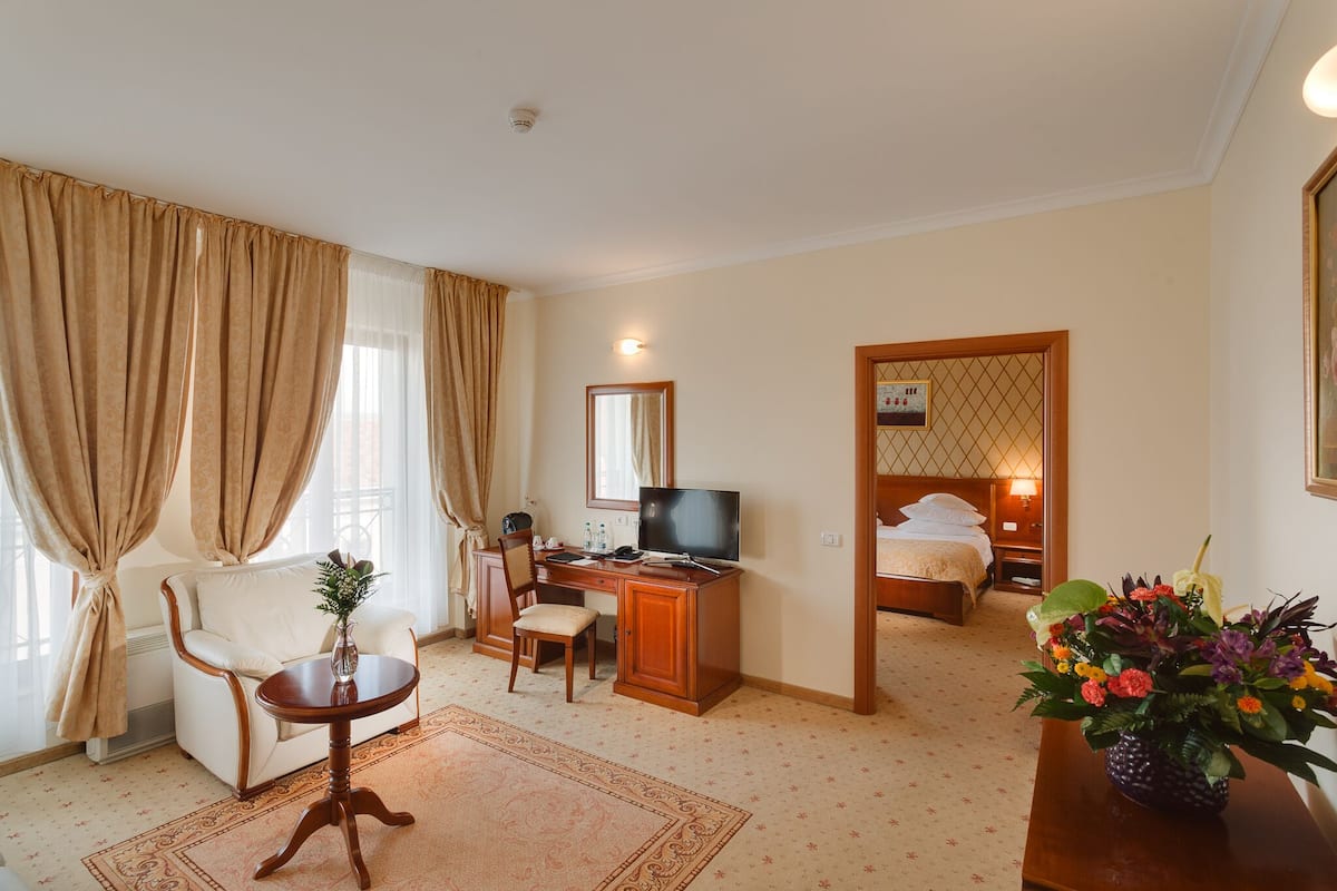 A hotel room with a sofa, desk, TV, and a bed.
