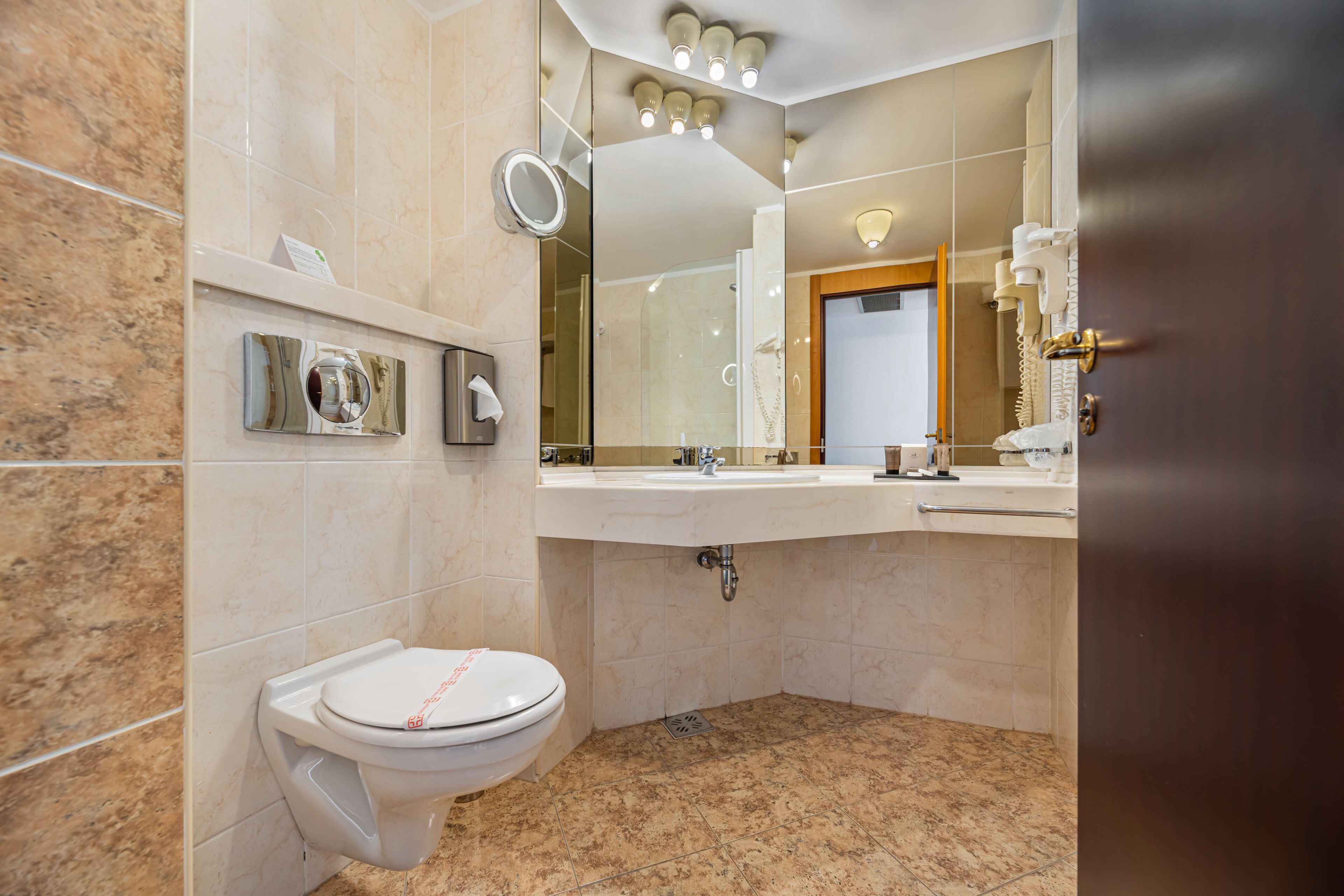 Un baño moderno con inodoro, lavamanos y espejo.