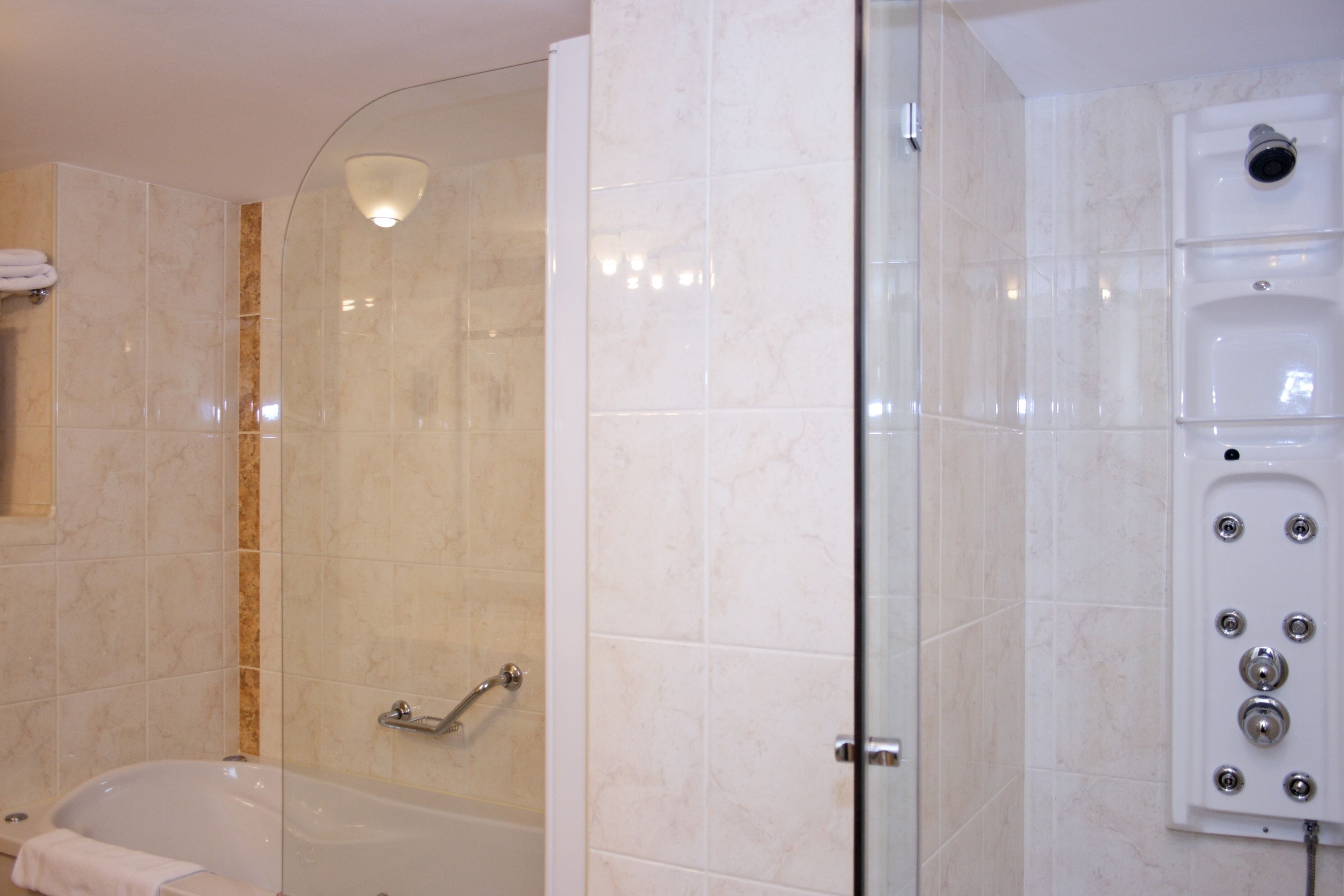 Une salle de bain moderne dotée d’une douche à parois de verre, d’une baignoire et d’une douche à vapeur intégrée.