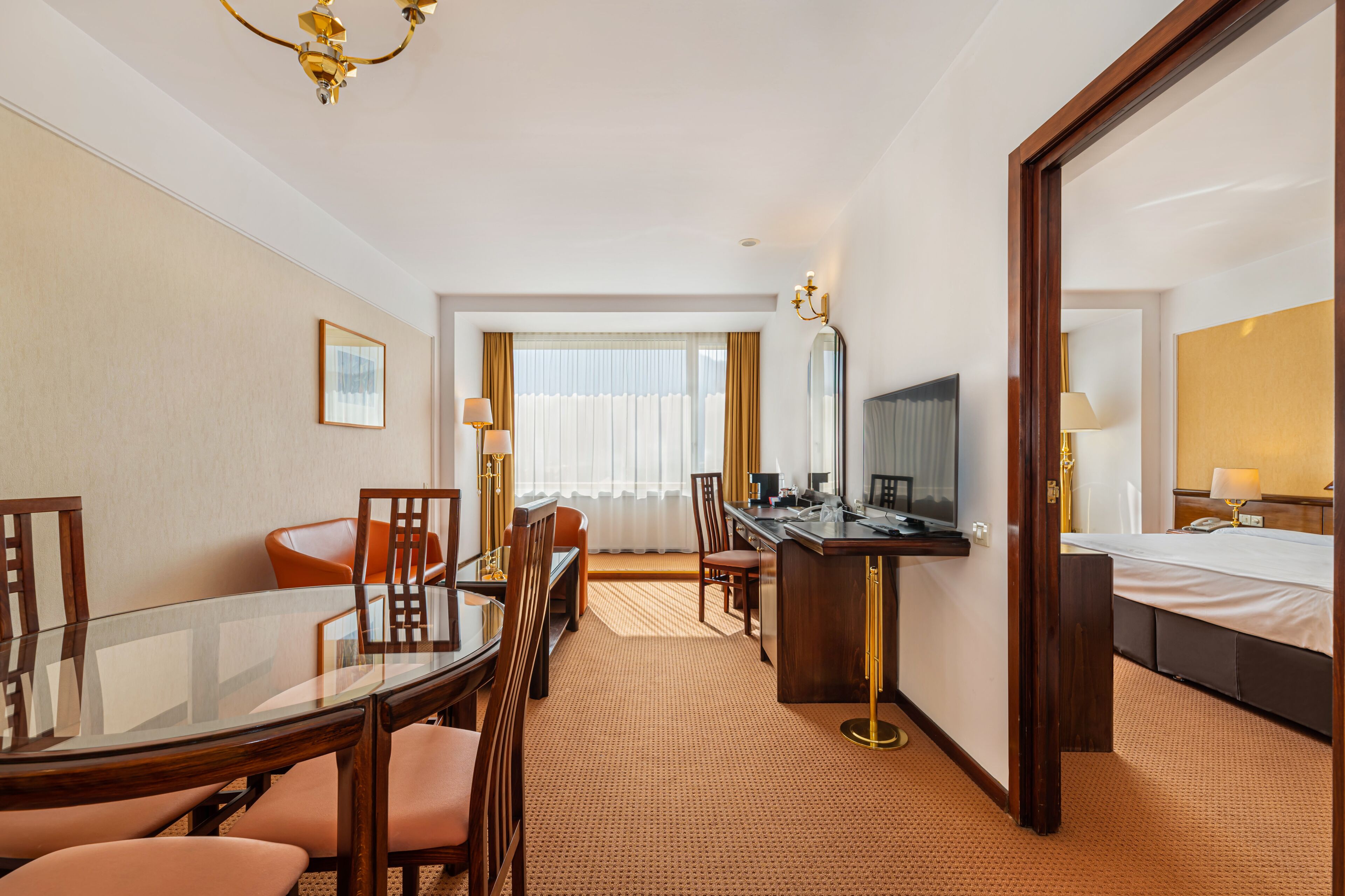Habitación de hotel con mesa de comedor, sillas, escritorio, cama y un espejo grande.
