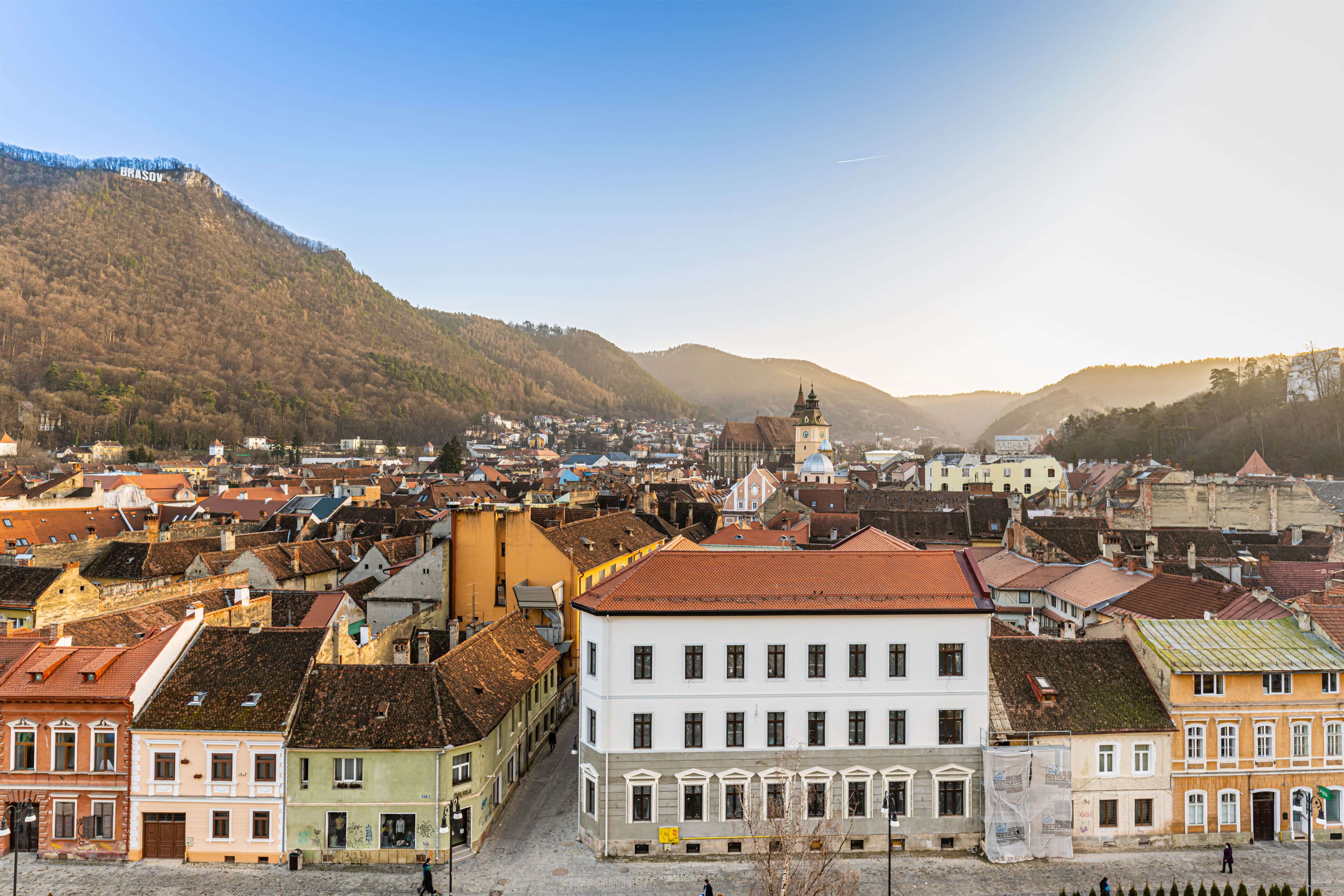 A historic town with a prominent church, colorful buildings, and a hilly backdrop.