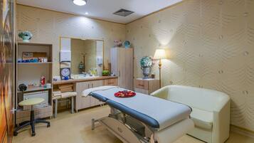 Un consultorio médico con una cama, mesa de exploración y un escritorio con material médico.