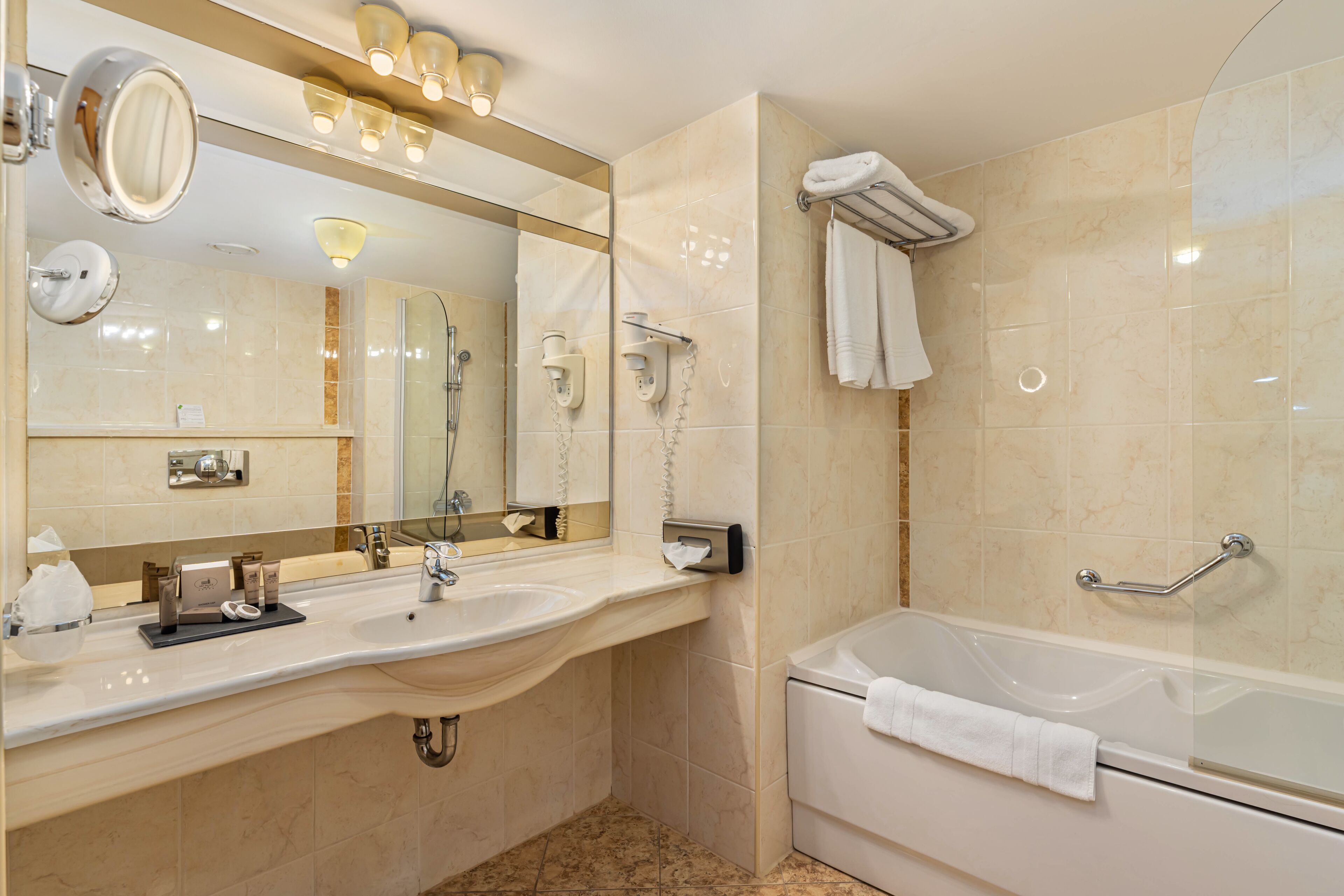 Un baño moderno con un espejo grande, un lavabo, una bañera y un perchero para toallas.