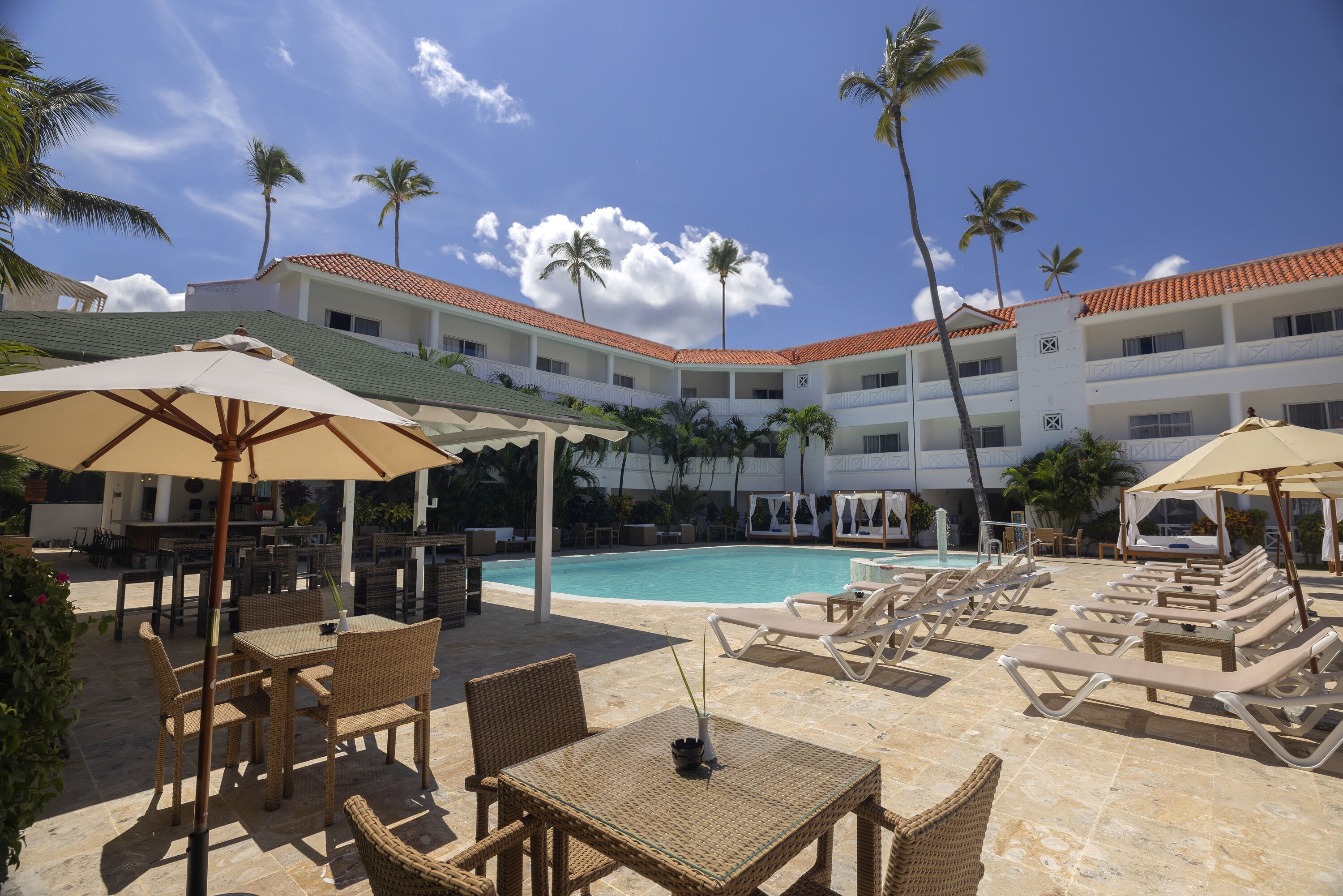 A poolside area with lounge chairs, umbrellas, and a dining setup.