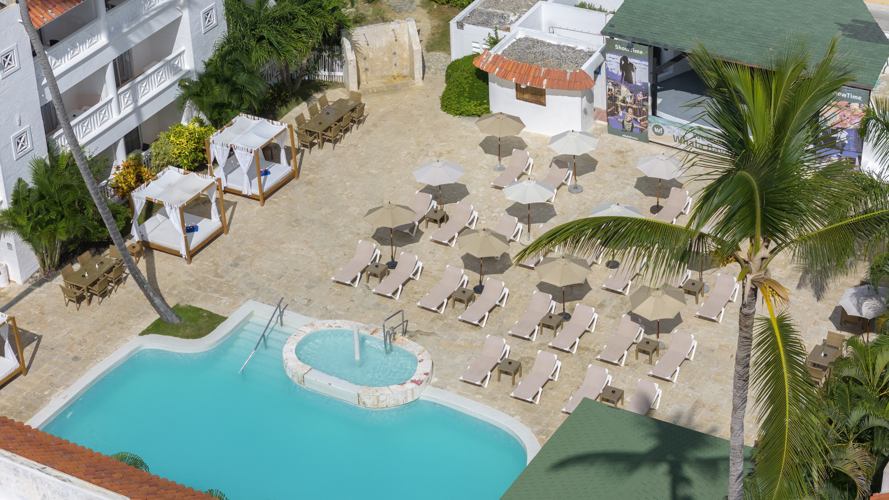Oversigtsbillede af et resort med swimmingpool, liggestole og parasoller.