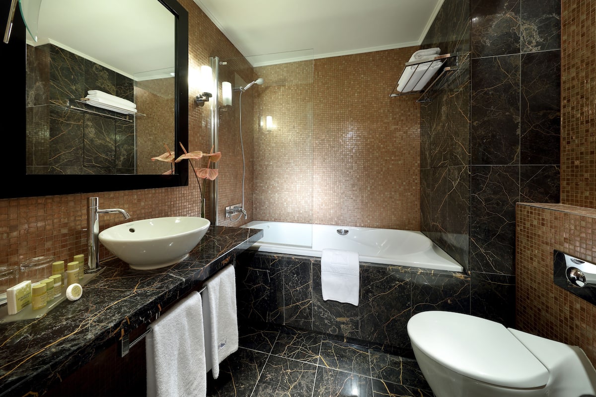 A modern bathroom with a large sink, bathtub, and toilet.