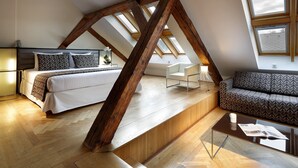 A loft bedroom with a bed, a sofa, a coffee table, and a skylight. - Eurostars Thalia (Prague)
