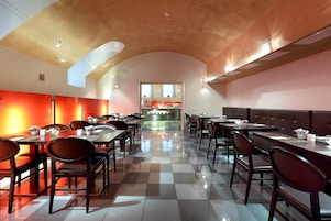 Um restaurante moderno com piso xadrez, teto de madeira e detalhes vermelhos nas paredes.