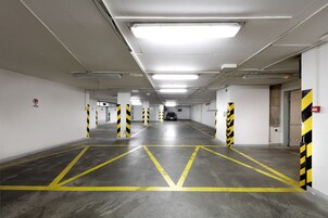Garagem de estacionamento limpa e bem iluminada, com vagas demarcadas e barreiras de segurança.