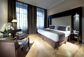 Una habitación de hotel moderna con una cama grande, un escritorio, una silla y una planta en maceta.