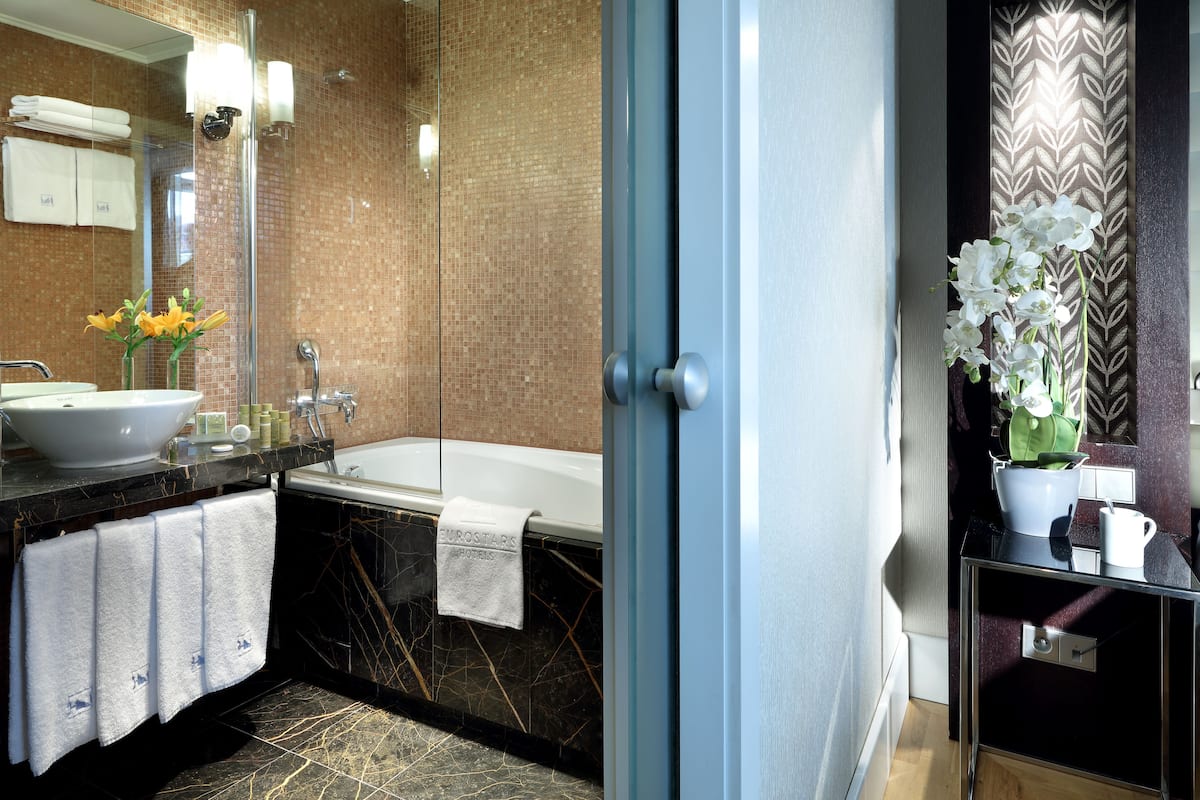 A modern bathroom with a large sink, bathtub, and a glass shower enclosure.