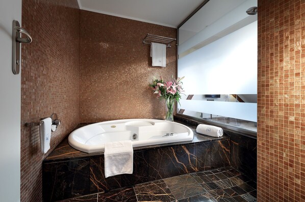 A modern bathroom with a freestanding bathtub, a marble countertop, and a mirror above the sink. - Eurostars Thalia (Prague)