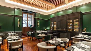 A restaurant with green walls, wooden ceiling, and multiple dining tables with chairs.