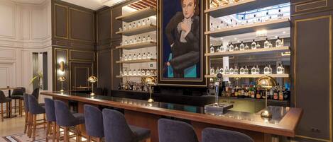 A bar area with multiple stools, shelves with bottles, and a large framed portrait.