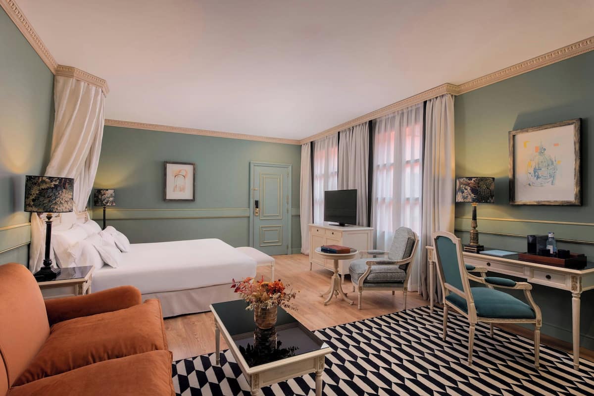 Een hotelkamer met een bed, een bureau, een stoel, een salontafel en een televisie.