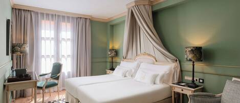 Habitación de hotel con una cama grande, dos mesitas de noche, una silla y un escritorio.