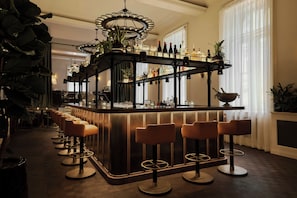 A bar area with a curved counter, multiple stools, and a variety of bottles and glasses. - Eurostars David (Prague)
