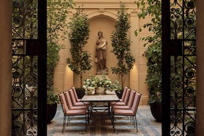 An outdoor dining area with a statue, surrounded by iron gates and potted plants. - Eurostars David (Prague)