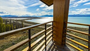 Un balcone in legno con vista su un lago e montagne.