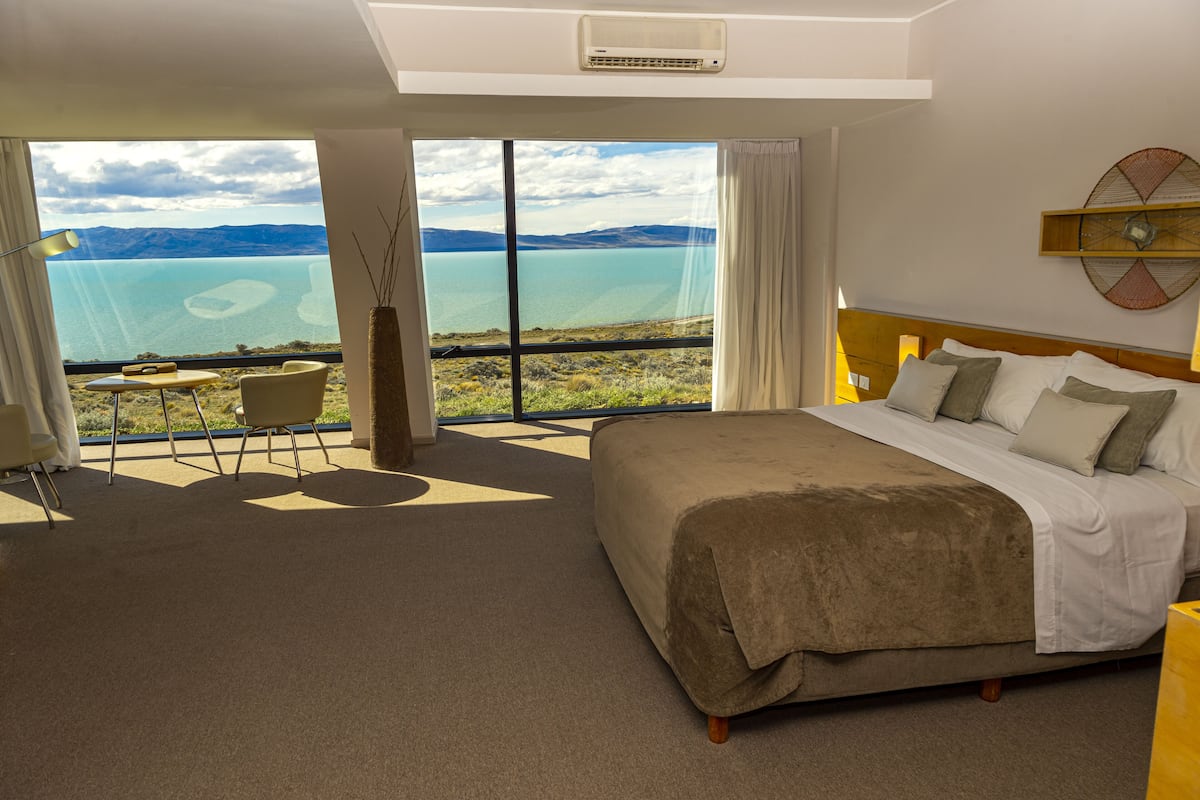 A bedroom with a large bed, a view of a lake, and a small table with chairs.