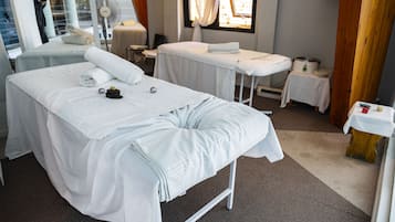 Comfortable room with a neatly made bed, small table, and wall-mounted fan.