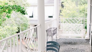 A covered porch with white railings, a ceiling fan, and a bench.