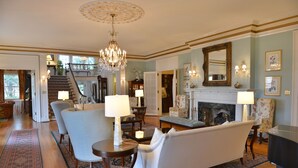 A spacious living room with a chandelier, a fireplace, and a staircase leading to an upper level. - Morehead Inn (Charlotte)