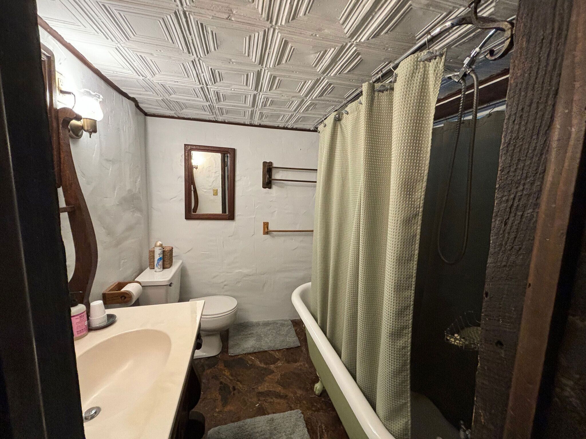 A bathroom with a white toilet, a sink, a mirror, and a shower with a green shower curtain.
