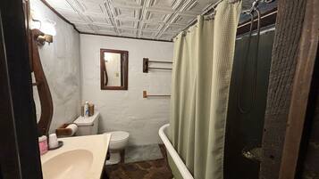 A bathroom with a white toilet, a sink, a mirror, and a shower with a green shower curtain.