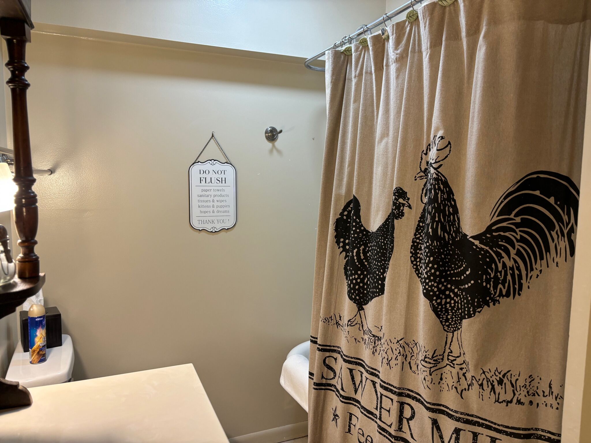 Casa de banho com cortina de chuveiro com um desenho de galo e o texto "SAWIER MINT".