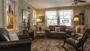 A living room with a sofa, chairs, a rug, and a ceiling fan.