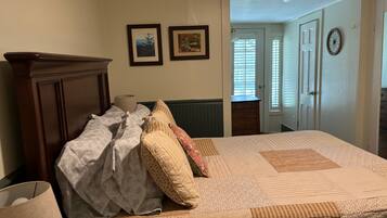 Un dormitorio con una cama, un aparador y una puerta que da a otra habitación.