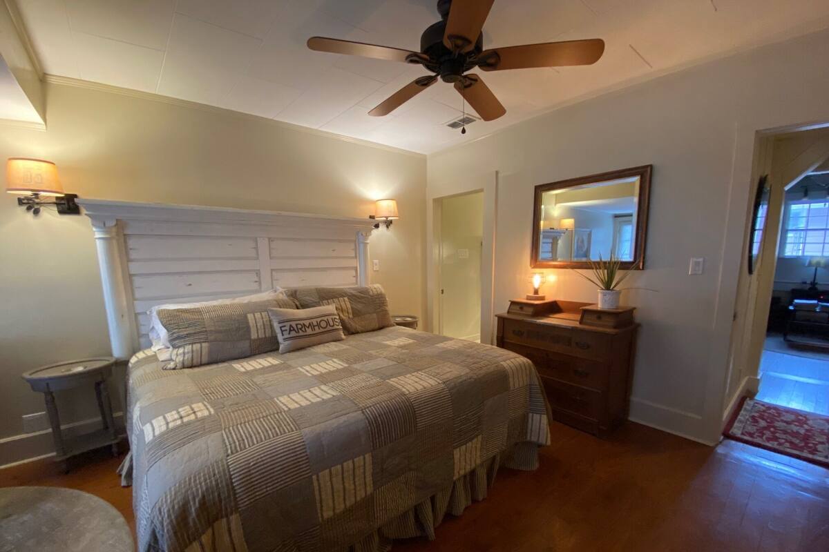 A bedroom with a bed, a dresser, a ceiling fan, and a mirror.