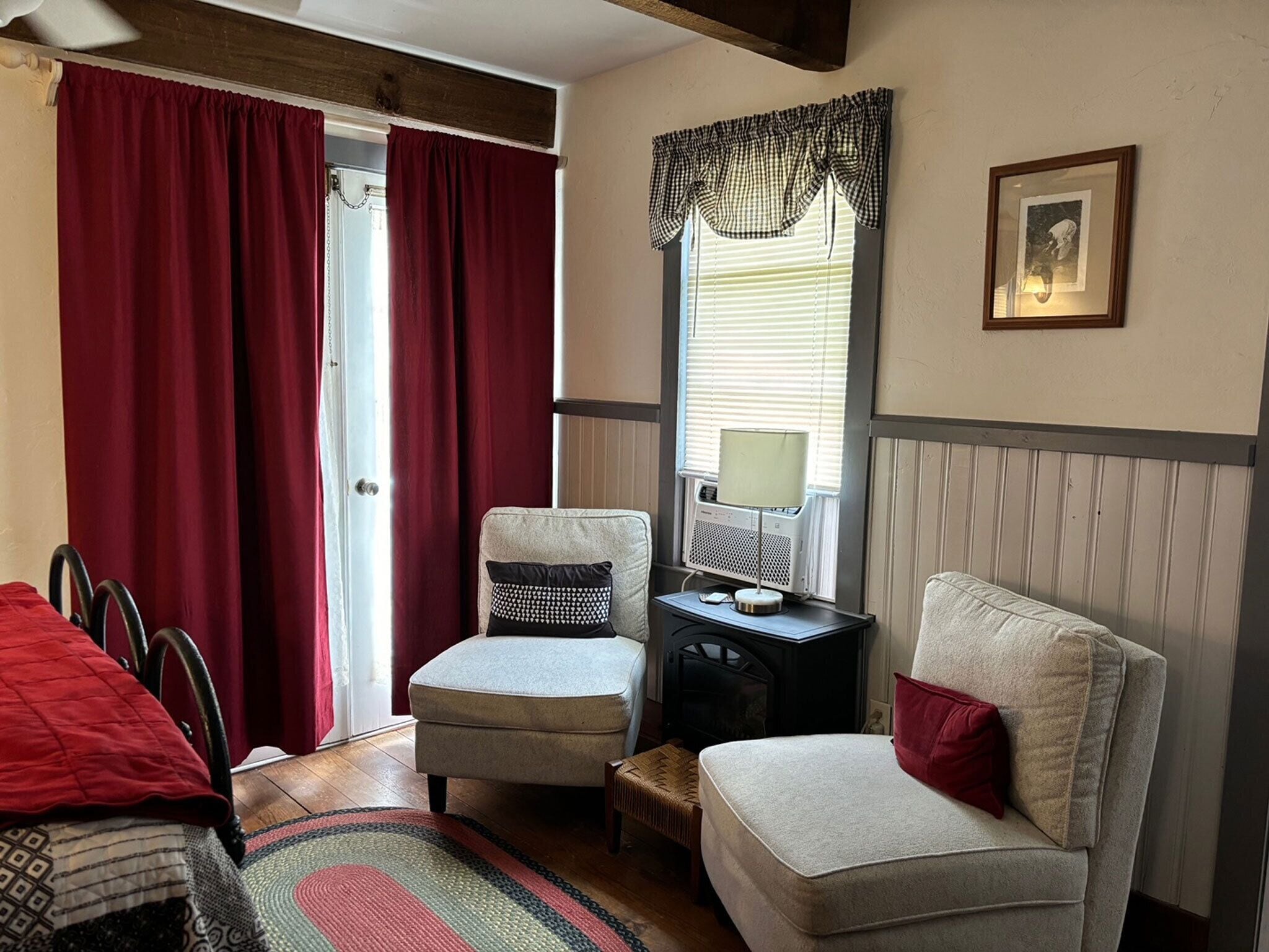 A cozy room with two armchairs, a small table with a lamp, and a window with curtains.
