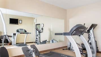 Un gimnasio con cintas de correr, una bicicleta estática y un banco para pesas.