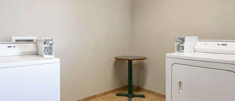 Une buanderie équipée de deux machines à laver et d’une petite table.