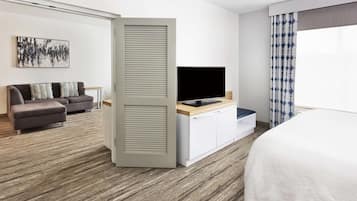 Una habitación de hotel con una cama, un televisor sobre un mueble de madera, un sofá y un cuadro en la pared.