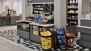 A modern retail area with a counter labeled "The Shop" stocked with snacks and beverages.